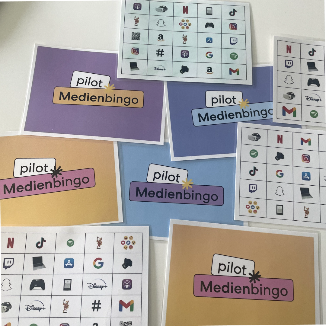 Mehrere bunte Bingokarten mit der Überschrift „Medienbingo“ auf einem Tisch.