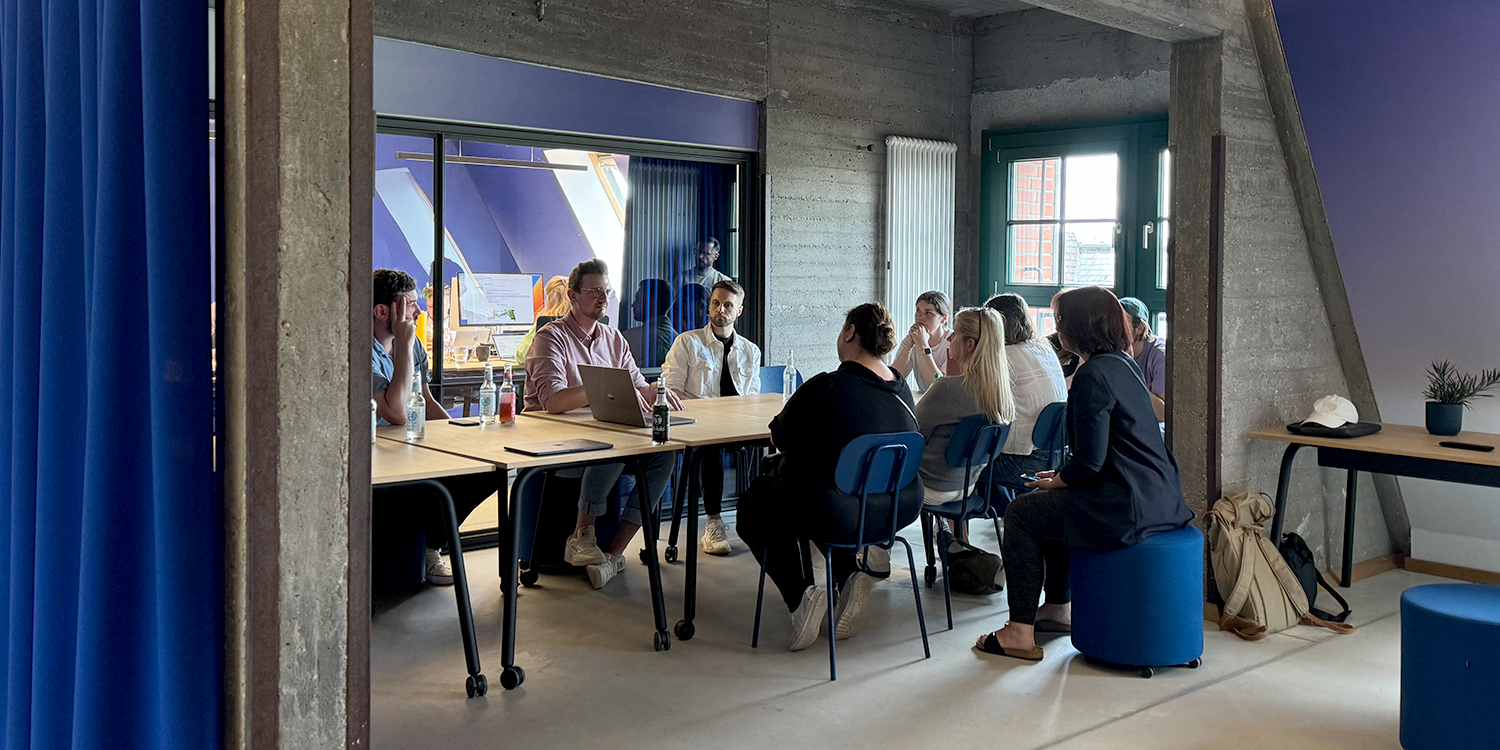 Eine Gruppe von Personen sitzt in einem modernen Konferenzraum und nimmt an einer Besprechung oder Diskussion teil.