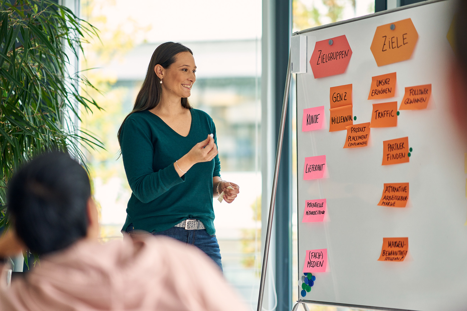 Eine Frau, die vor einem Whiteboard steht und eine Präsentation hält.