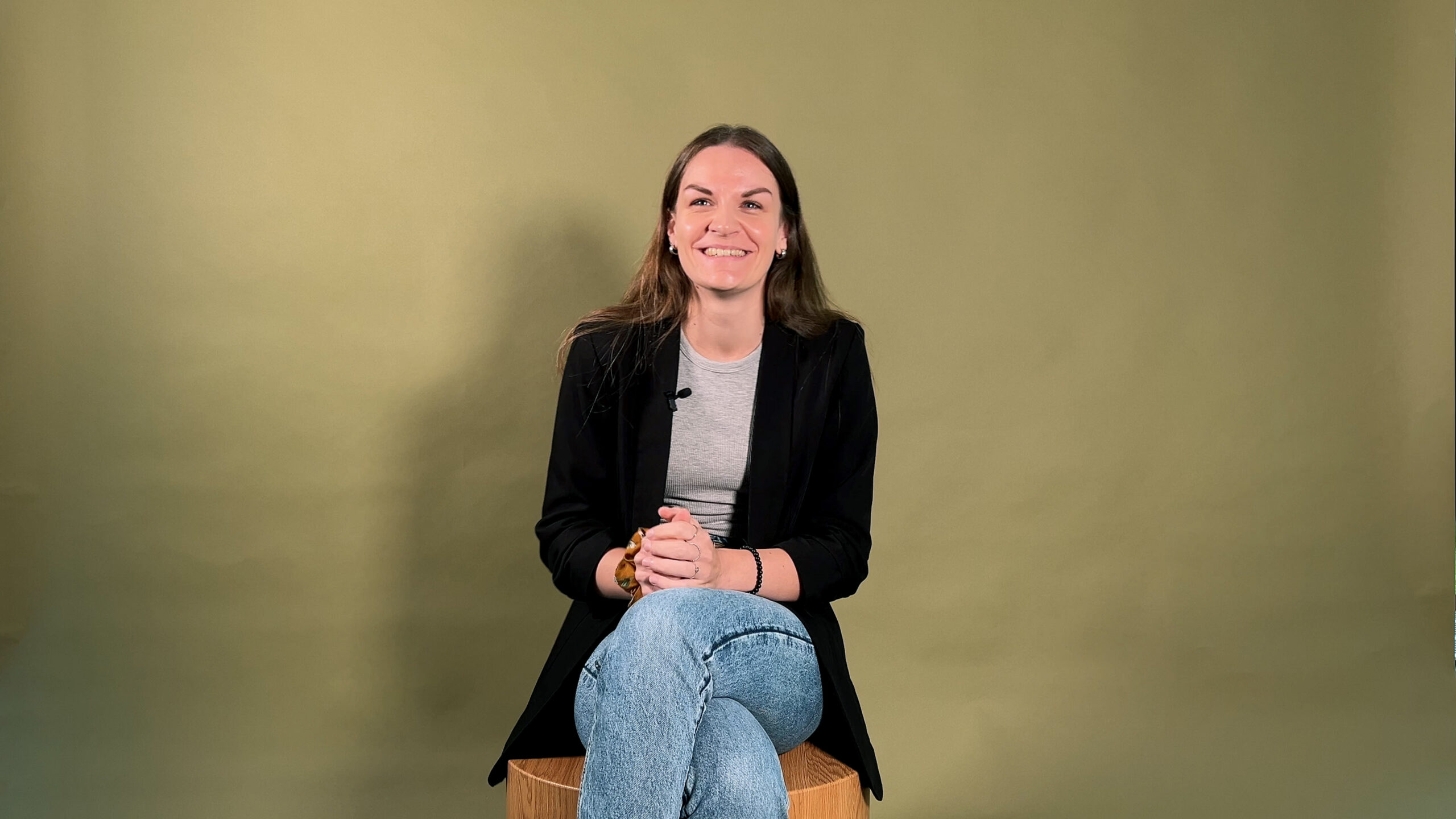 Junge Frau sitzt auf einem Stuhl vor einem Greenscreen