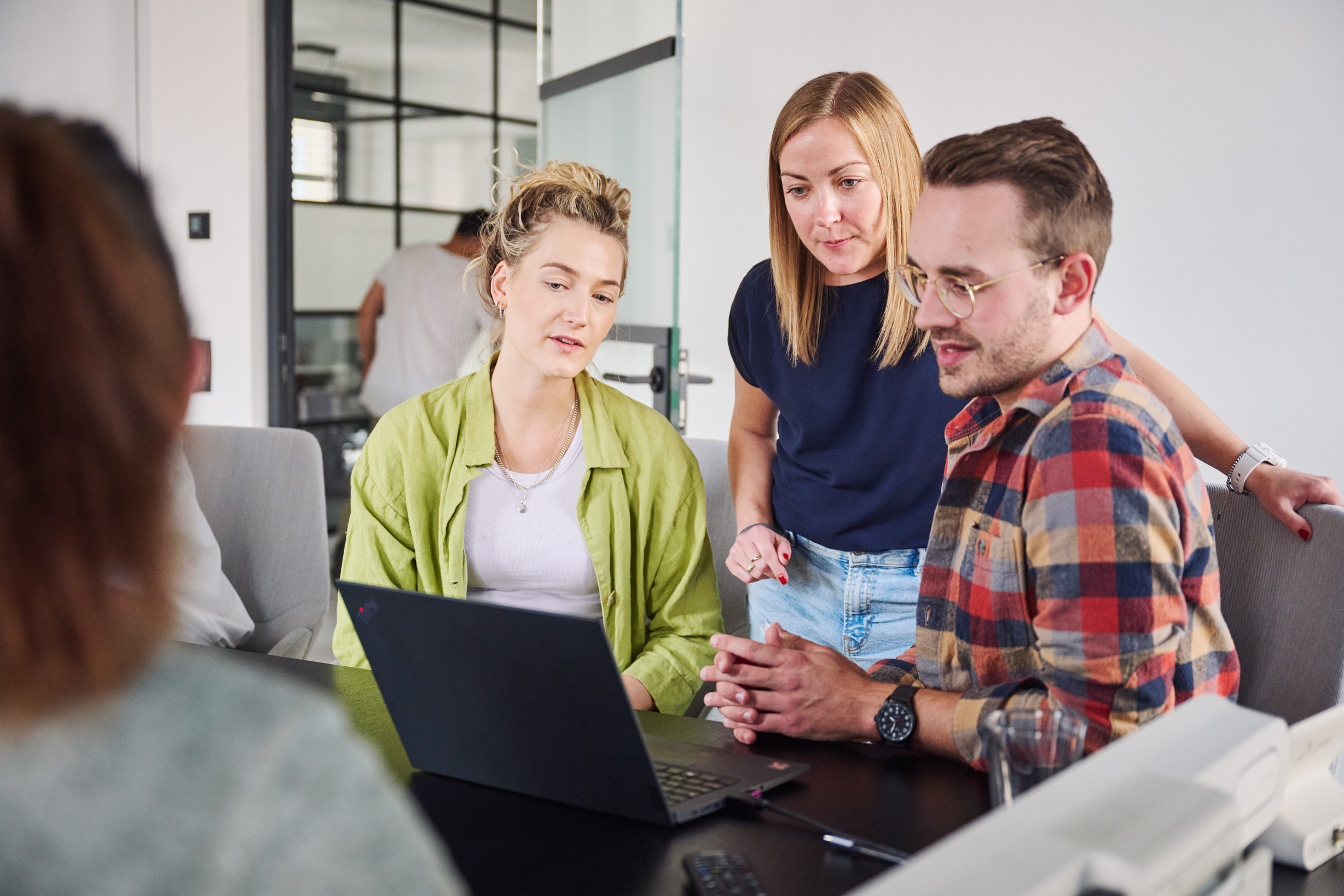 Vier Menschen sitzen um einen Laptop