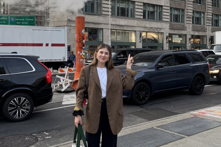 Frau steht vor Kreuzung in New York, Verkehr im Hintergrund