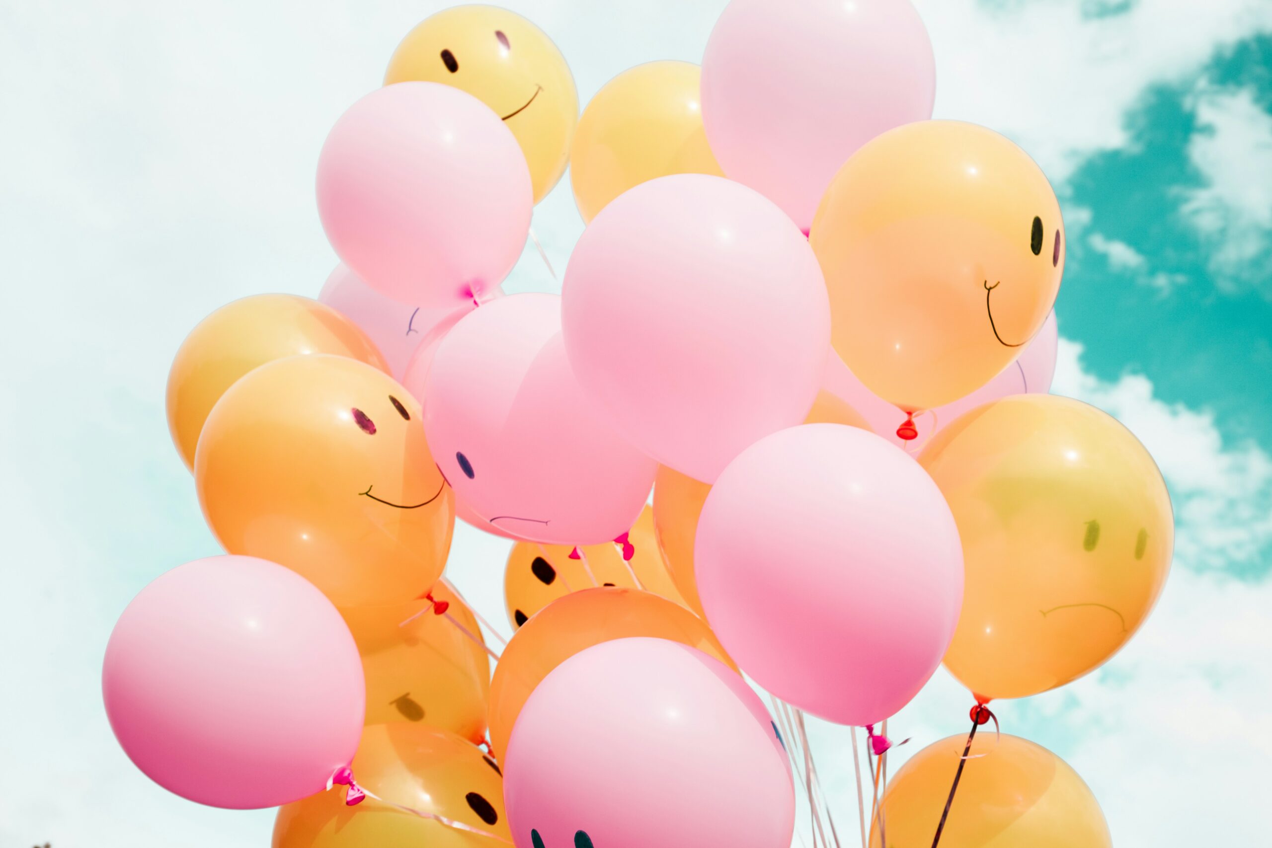 pinke und orange farbene Luftballons mit lachenden Gesichtern