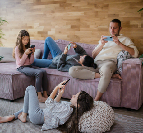 Familienmitglieder sitzen auf der Couch und haben alle ein Smartphone in der Hand